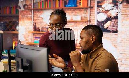 Teamworking programmers creating deep learning models analyzing data in artificial intelligence development agency. African american IT coworkers programming in AI startup office, camera B Stock Photo