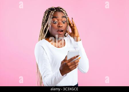 Shocked African American woman looking at smartphone Stock Photo