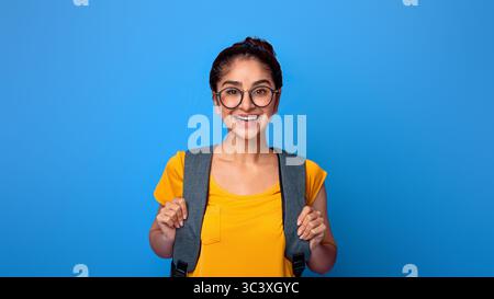 Happy indian female student wearing backpack and eyeglasses Stock Photo