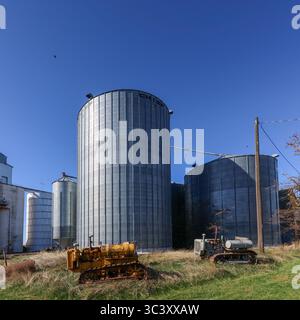 Two rusty old tractors in front of grain elevators in Hartline WA Stock Photo