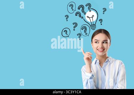Young businesswoman with raised index finger, drawn light bulb and question marks on blue background. Business idea concept Stock Photo
