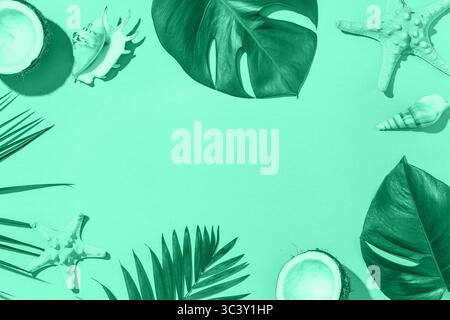 Frame made of coconuts, seashells and tropical leaves on mint background with space for text Stock Photo