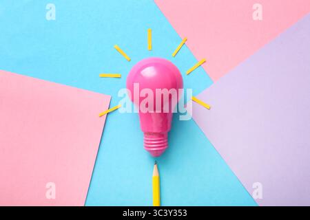 Pink light bulb with paper sheets on blue background Stock Photo