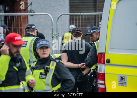 London, UK. 27th July, 2025. An anti-migrant protestor is temporarily detained and searched for weapons by the Police outside the Bell Hotel in Epping. Thousands of anti-far-right counter-protestors marched to Bell Hotel in Epping to oppose the anti-migrant demonstrators rallying outside the hotel for the third weekend in a row. A huge police presence kept the two opposing groups separated by penning the anti-migrant demonstrators in behind fences. (Photo by Lab Ky Mo/SOPA Images/Sipa USA) Credit: Sipa USA/Alamy Live News Stock Photo