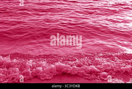 Stunning surreal pop art of raspberry pink waves splashing on the beach Stock Photo