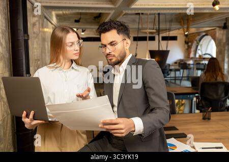 Two young professionals working in the office and looking involved Stock Photo