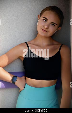 Young woman confidently posing in a fashionable outfit against a contemporary backdrop, highlighting her unique style and vibrant personality Stock Photo