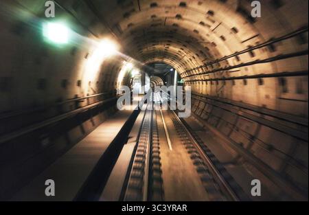 Long exposure captures the dramatic motion of a metro train moving through a tunnel. Bright lights and blurred lines create a sense of speed and depth Stock Photo