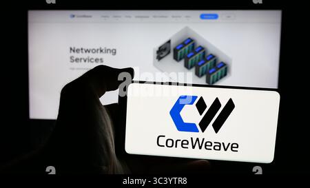 Stuttgart, Germany - 06-07-2025: Person holding mobile phone with logo of US AI cloud computing company CoreWeave Inc. on screen in front of web page. Stock Photo