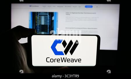 Stuttgart, Germany - 06-07-2025: Person holding cellphone with logo of US AI cloud computing company CoreWeave Inc. on screen in front of webpage. Stock Photo