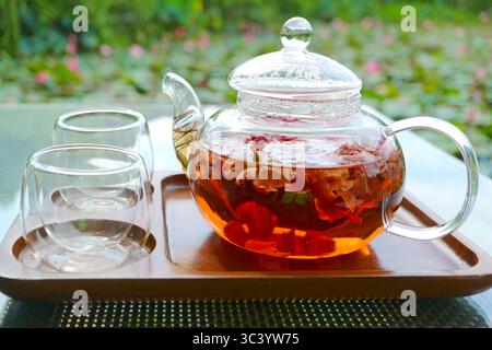 Closeup of rose tea being steeped in a teapot on garden table Stock Photo