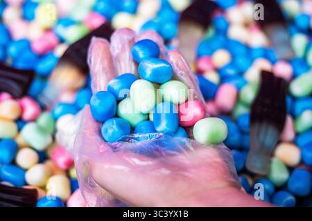picking up jelly candies with a hand in a disposable glove for purchase Stock Photo
