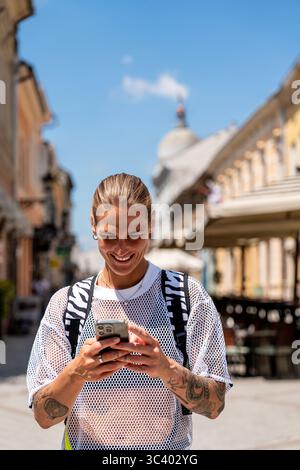 Trendy young urban woman using smartphone on European city street while traveling Stock Photo