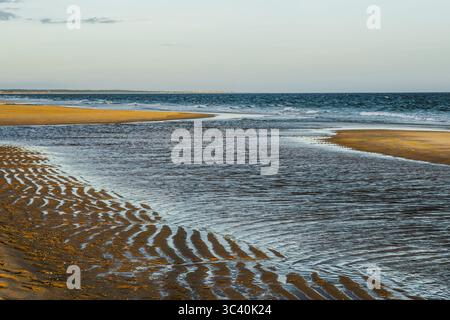 Patterns in the wet sand created by low tide along the coastline. Stock Photo