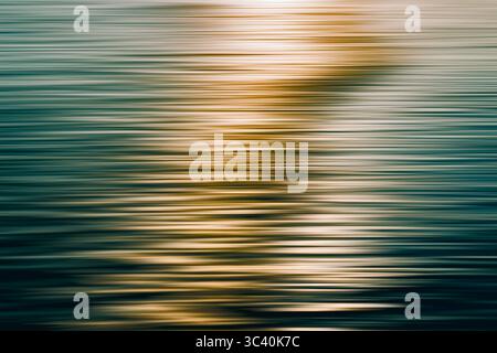 Blurred sunset reflection over the ocean with soft golden tones, abstract Stock Photo