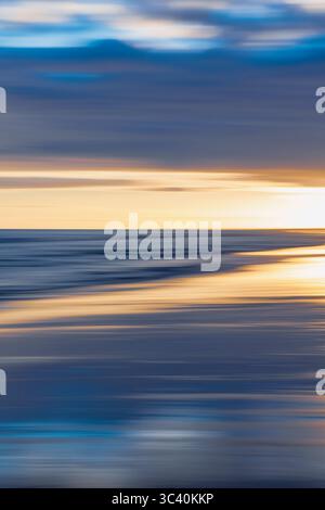 Blurred seascape with soft streaks of blue and golden hues. Stock Photo