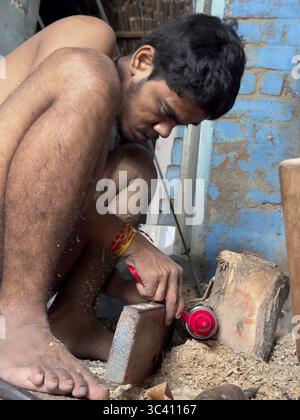 A young man works intently with wood in a rustic workshop, Varanasi, Uttar Pradesh, India Stock Photo