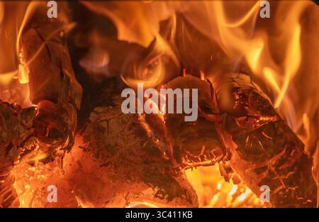 Close-up of flames of log fire burning enclosed space. Winter heating by enclosed log-burning stove in Australian house. Glass window in door. Hot. Stock Photo