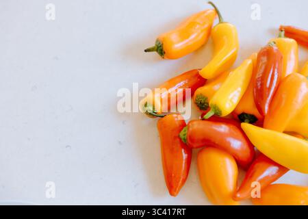 Colorful sweet mini peppers resting on white countertop Stock Photo
