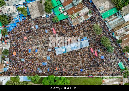 Aerial view of a vast gathering of people filling a dusty expanse amidst buildings and scattered colorful tarps, Mahasthan, Rajshahi Division, Bangladesh. Stock Photo