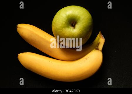 Still Life of Fresh Green Apple and Ripe Bananas on Black Background Stock Photo