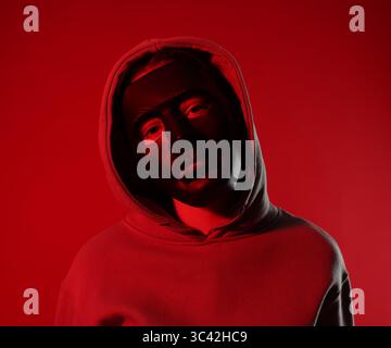 Anonymity. Woman wearing mask on red background Stock Photo