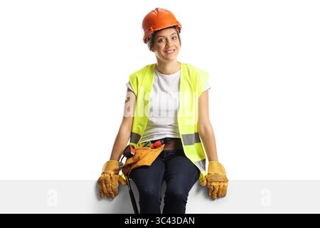 Female construction worker sitting on a blank panel isolated on white background Stock Photo