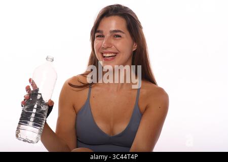 young smiling woman holding water bottle in her hand against white background Stock Photo