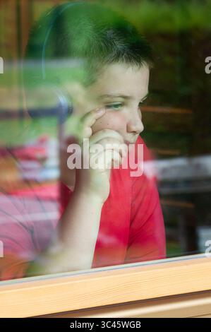 Boy Listening Music on Headphones and Looking out of Window Stock Photo
