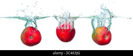 Group of bright red apples splashing into clear water, creating dynamic bubbles and droplets against a stark white background, highlighting freshness Stock Photo