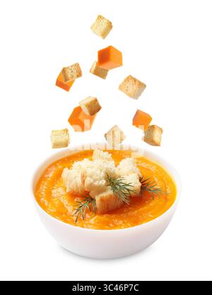 Croutons and pumpkin cubes falling into bowl of soup against white background Stock Photo