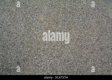 Close-up of a speckled asphalt surface, showcasing its rough and granular texture, ideal for background use or urban themes. Stock Photo
