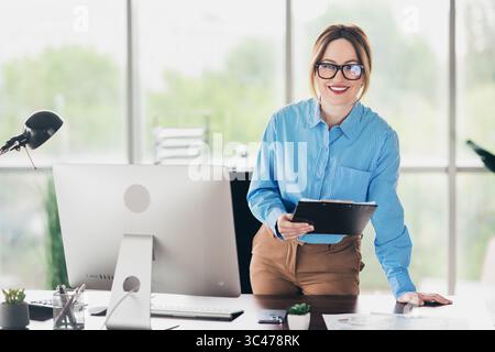 Successful businesswoman working confidently in a modern office environment with formal attire and professional tools Stock Photo