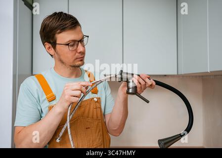 Professional plumber carefully connecting flexible water supply lines to a new modern kitchen faucet, ensuring proper installation and leak-free functionality Stock Photo