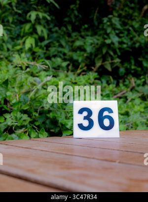 Number 36 on a wooden table with a green background. Could be used for age, address, or other numerical concepts. Stock Photo