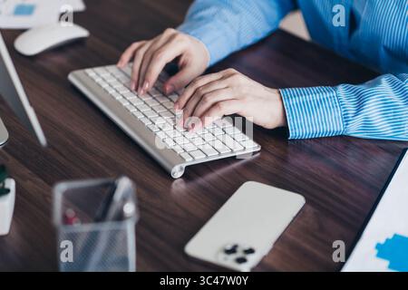 Professional businesswoman working at her desk using a keyboard in a contemporary office setting Stock Photo