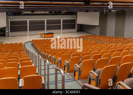 Empty university lecture hall with seen from the rear with empty seats and professor's desk. Stock Photo