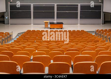 Empty university lecture hall with seen from the rear with empty seats and professor's desk. Stock Photo