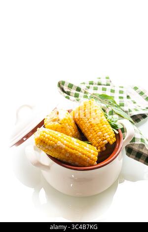 Two boiled corn cobs with dill on a white background. Stock Photo