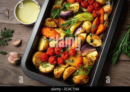 Oven roasted seasonal vegetables with spices and herbs on baking tray. Vegetarian vegan organic autumn meal or side dish - baked vegetables. Stock Photo