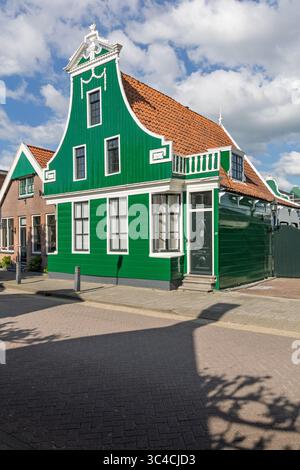 This eye-catching image showcases a vibrant green traditional Dutch wooden house with a classic gabled roof, standing proudly on a street with other b Stock Photo