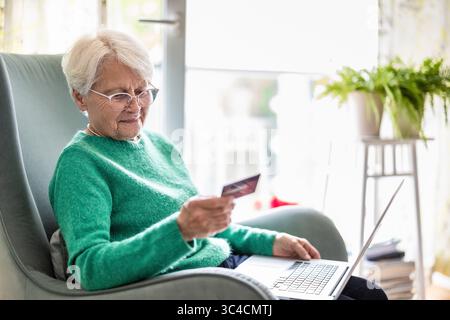 Senior woman using laptop and credit card for online shopping at home Stock Photo