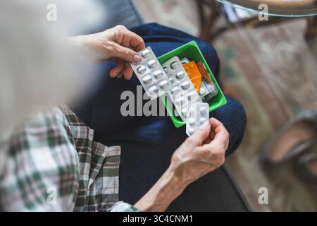 Unrecognizable elderly woman taking her medication at home, close-up of woman’s hands Stock Photo
