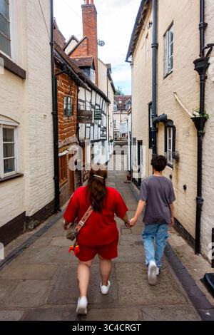 Mother and son walking together down a narrow street or pathway in Bridgnorth, Shropshire, UK Stock Photo