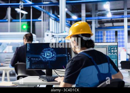 Engineer developing AI diagnostics tool in photovoltaic factory to predict component failures. Solar panels plant technician coding artificial intelligence algorithms to enhance predictive maintenance Stock Photo