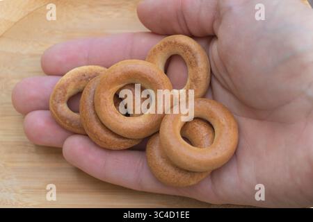 Small Round Bagel-Style Crackers Held in Hand on Wooden Background. Stock Photo