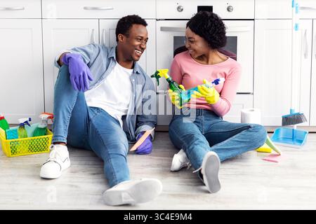 Relaxed african american family sitting on floor with cleaning tools Stock Photo