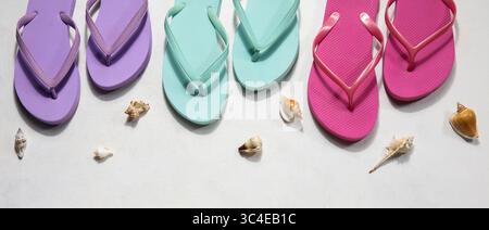 Colorful flip flops with seashells on light background, top view Stock Photo