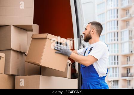 Male mover unloading boxes from car on street Stock Photo