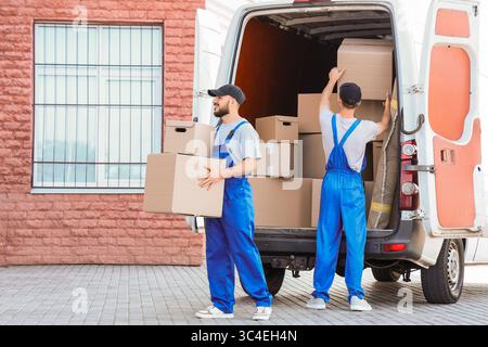 Male movers unloading boxes outdoors Stock Photo